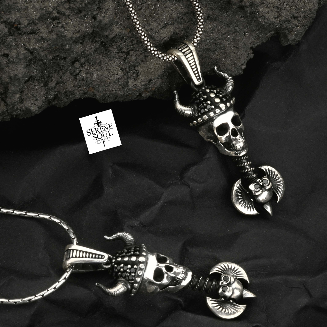 Two silver skull pendants on a dark fabric background with 'Serene Soul' branding.