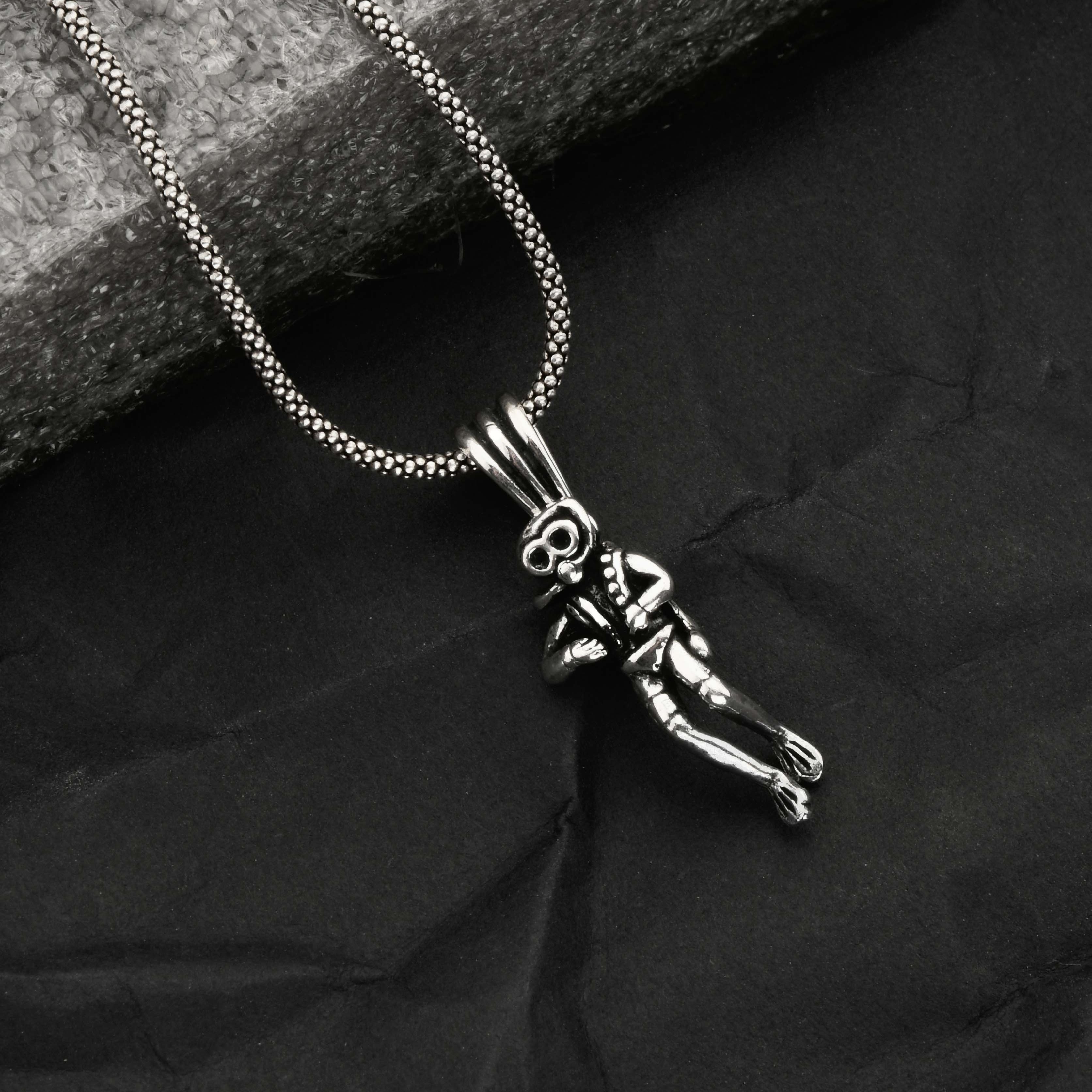 Silver necklace with a pendant on a dark fabric background