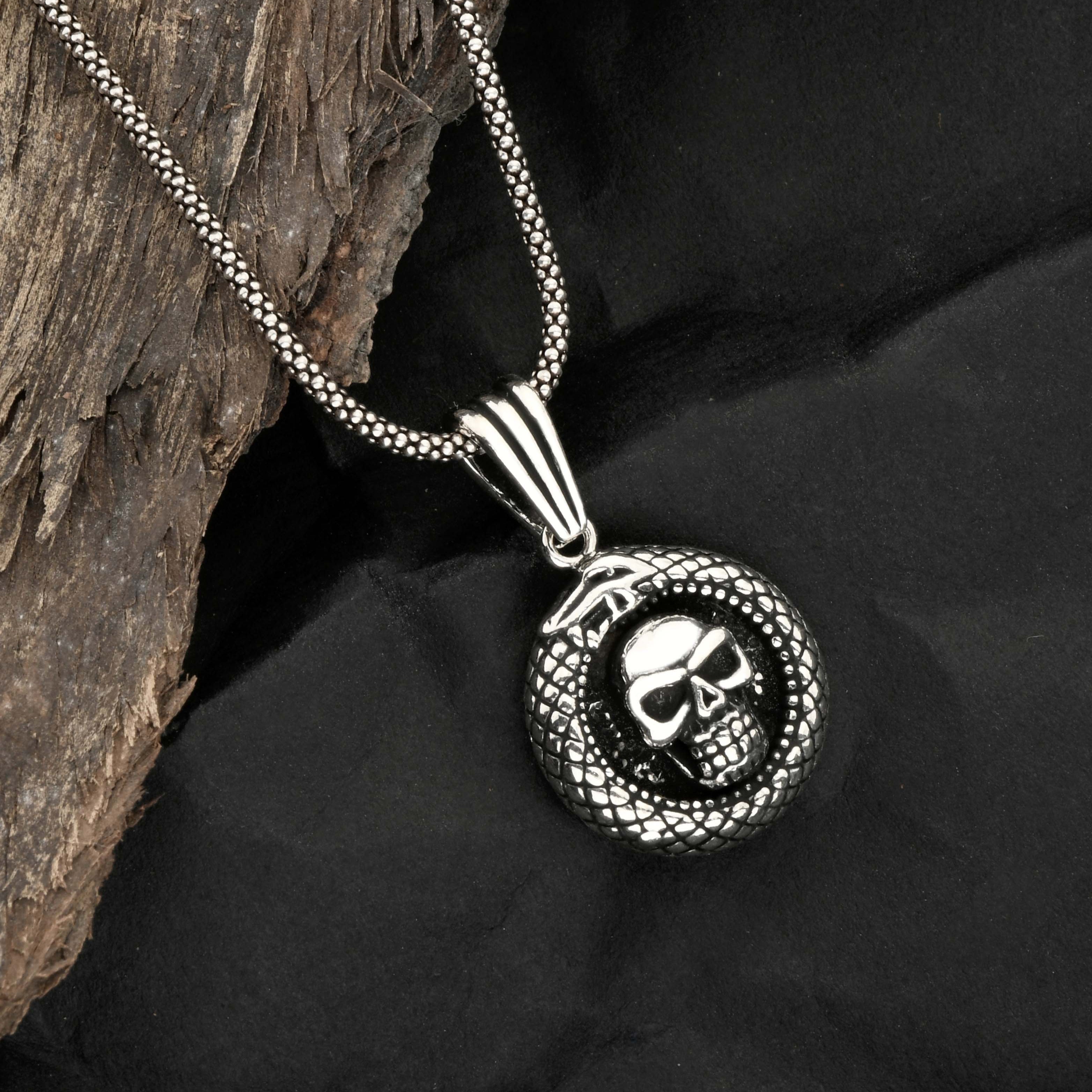 Silver necklace with skull pendant on a dark fabric background