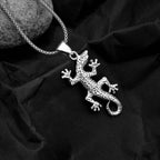 Silver lizard pendant on a chain against a black fabric background