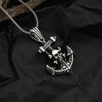 Silver pendant with anchor and skull design on a dark fabric background