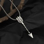 Silver arrow-shaped pendant necklace on a black fabric background