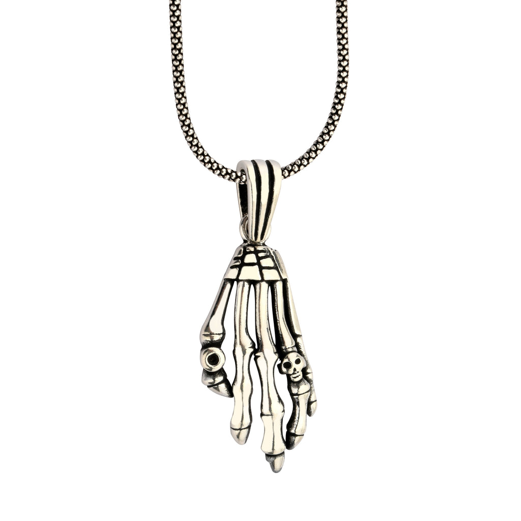 Silver skeleton hand pendant on a chain against a white background