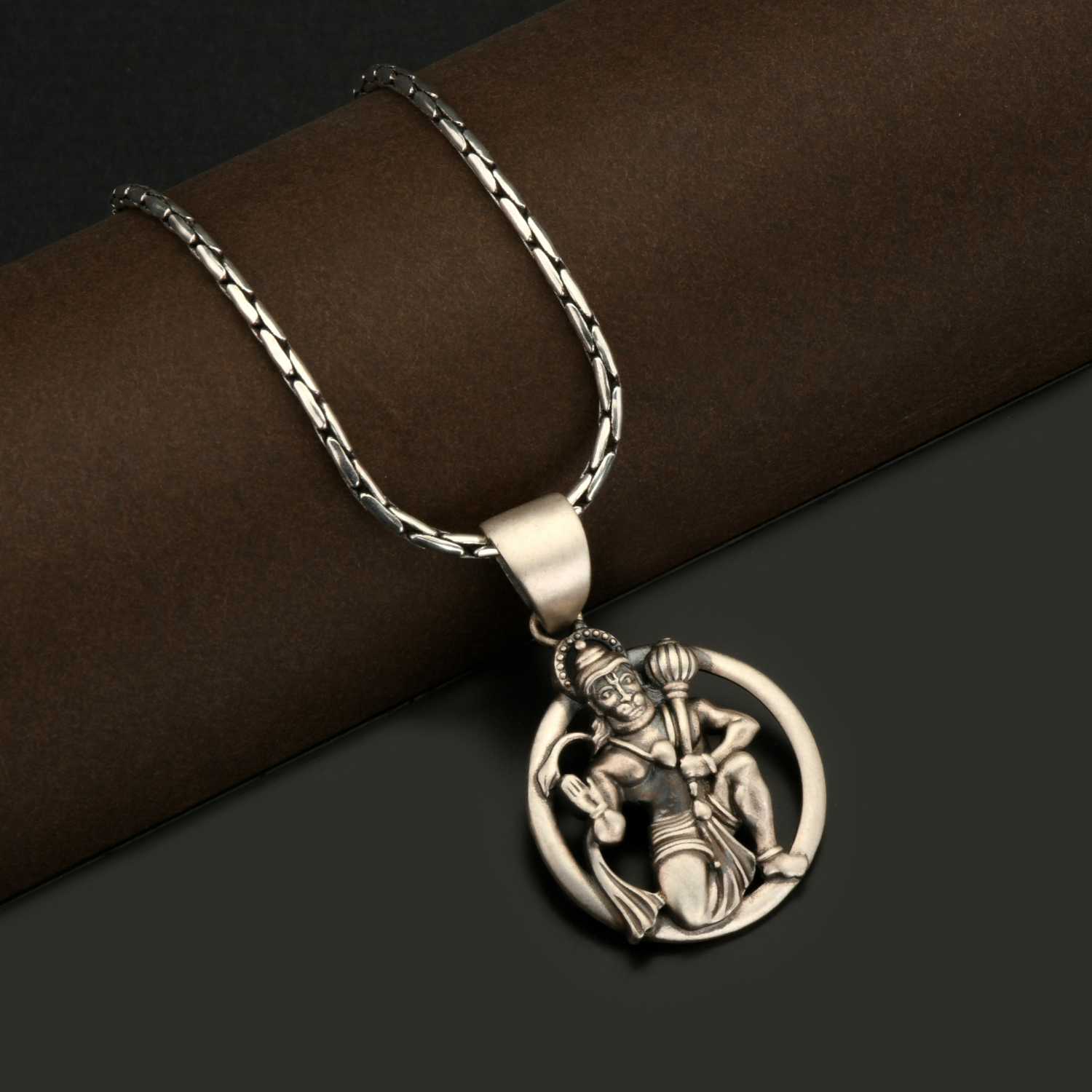 Silver necklace with a detailed pendant on a dark background