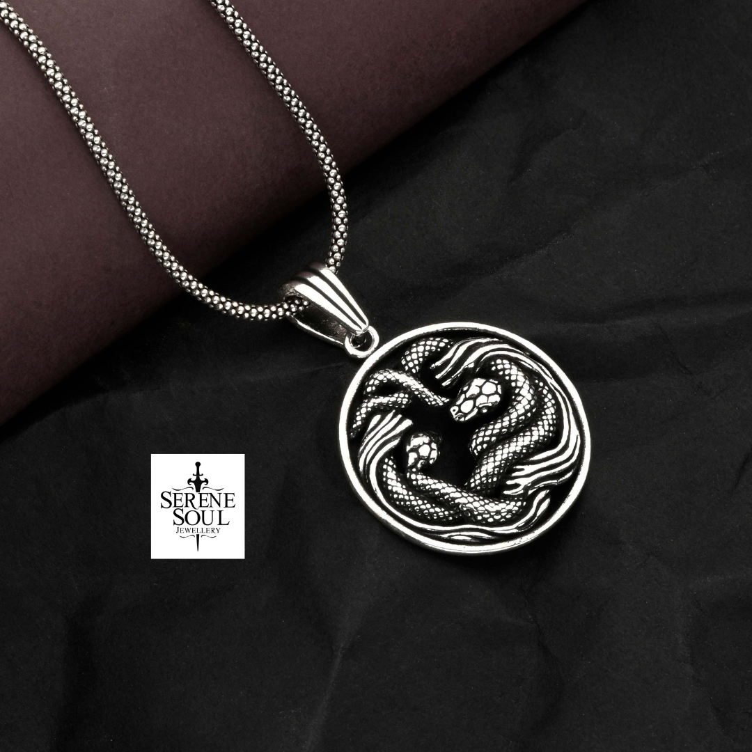 Silver pendant with snake design on a dark fabric background, featuring 'Serene Soul' jewelry brand.